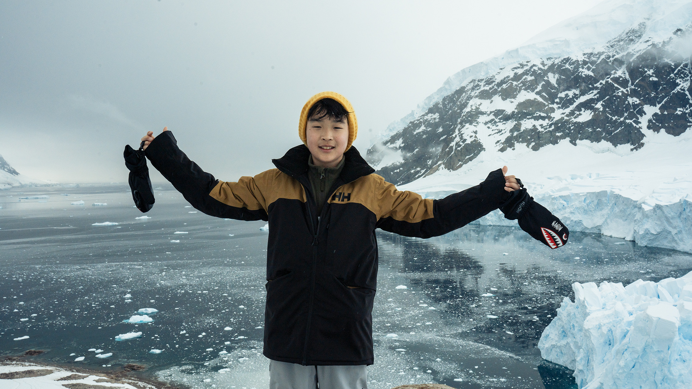 Sky standing beside icy water and snow-covered mountains in Antarctica